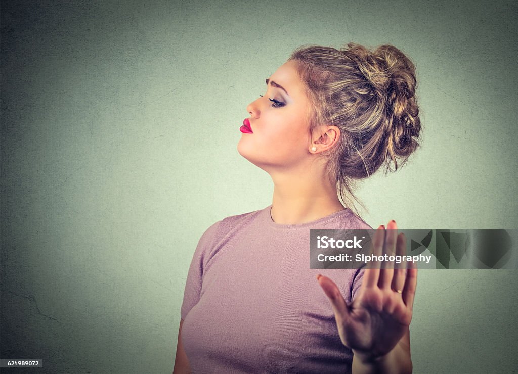 Snobby annoyed woman giving talk to hand gesture Snobby young annoyed angry woman with bad attitude giving talk to hand gesture with palm outward isolated grey wall background. Negative human emotion face expression feeling body language Snob Stock Photo