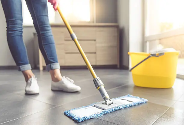 Cropped image of beautiful young woman in protective gloves using a flat wet-mop while cleaning floor in the house