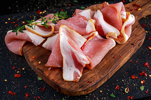 istock Raw smoked bacon slices on wooden board which herbs 624992216