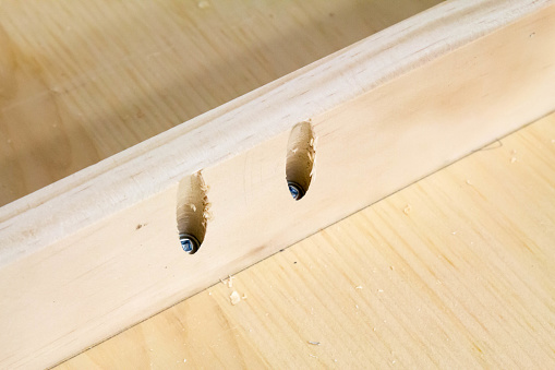 Two pocket screws are joining wood.  The wood is diagonal across the frame.  Pocket screws are often used in cabinet making and in woodworking projects.  The screw heads can be seen in the pocket holes.