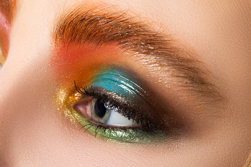 Close-up view of women eye with beautiful modern make-up. Multicolored somey eyes. Wet makeup.