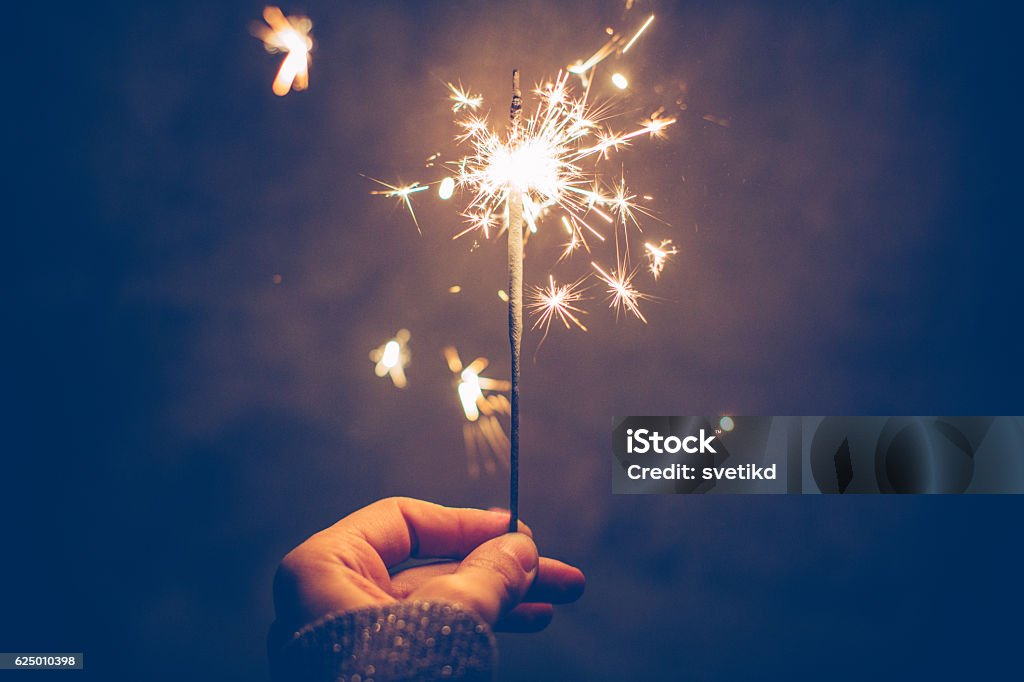 Sparkly night Close up of woman's hand holding sparklers on dark bakground. Sparkler - Firework Stock Photo