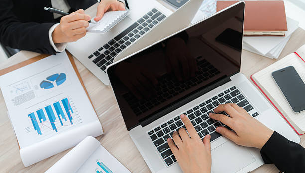 istock People typing on laptops surrounded by financial charts 625049960