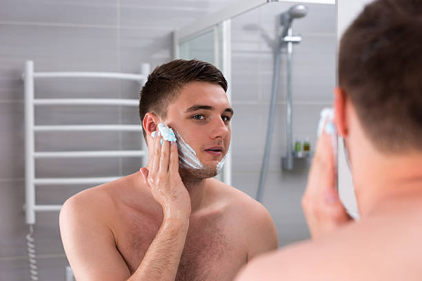 istock Guy smearing shaving gel on his face in the bathroom 625063670