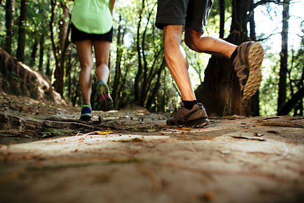 istock Low section of husband and wife running in forest 625064554
