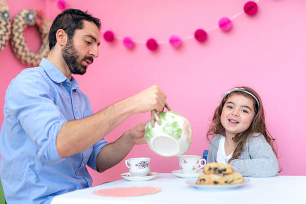 istock Cute young girl smiling while dad pours tea 625070186