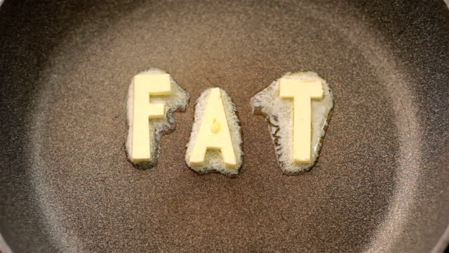 Butter in shape of the word fat melting on hot pan