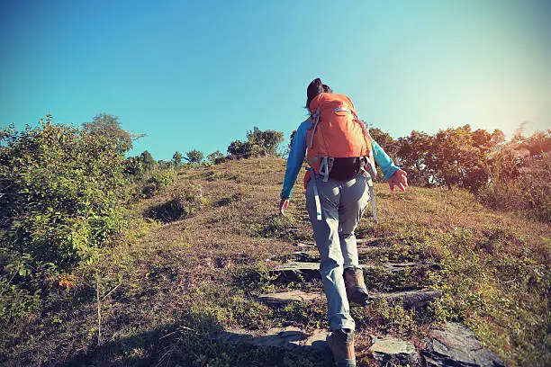 Photo of young woman backpacker trekking at mountain peak