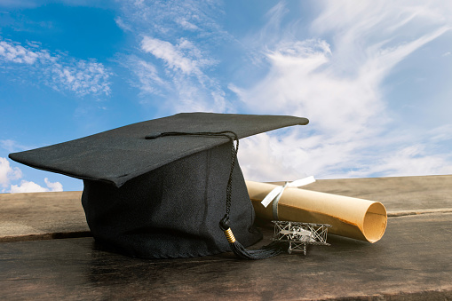 graduation cap, hat with degree paper on wood table, sky background Empty ready for your product display or montage.