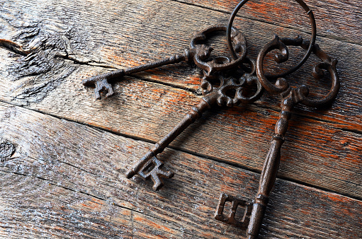 A top view image of three antique keys on a wooden table top.