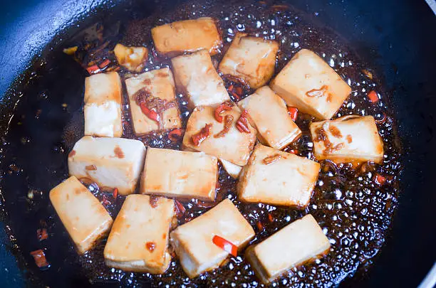 Detail of Tofu with chili and ginger cooking in a pan with soy sauceDetail of Tofu with chili and ginger cooking in a pan with soy sauce