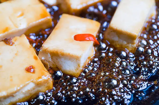 Detail of Tofu with chili and ginger cooking in a pan with soy sauceDetail of Tofu with chili and ginger cooking in a pan with soy sauce
