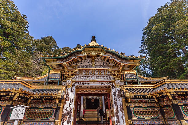 Nikko, Japan - April 15, 2014: A shinto priest sweeps under the Yomeimon gate on April 15, 2014 in Nikko, JP. Founded in 1617, the remains of the first shogun Tokugawa Ieyasu are entombed here.