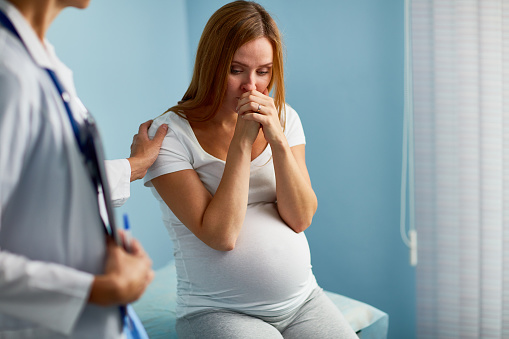 Pregnant woman crying with her doctor near by