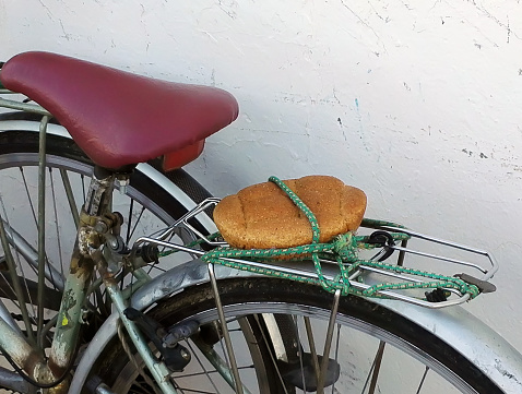 loaf of bread attached to trunk of an old bicycle