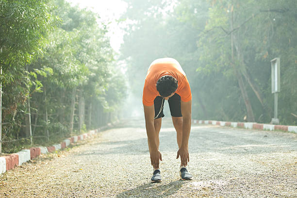 Jogger warming up at park Fit young male stretching at park, getting ready for jogging touching toes stock pictures, royalty-free photos & images