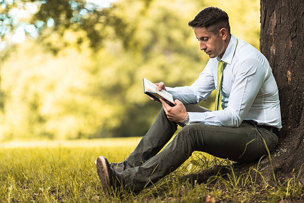 istock Relaxed businessman reading a novel in the park. 625136072