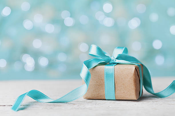 Christmas gift box against turquoise bokeh background. Holiday concept. Christmas gift box against turquoise bokeh background. Holiday greeting card. christmas paper photos stock pictures, royalty-free photos & images