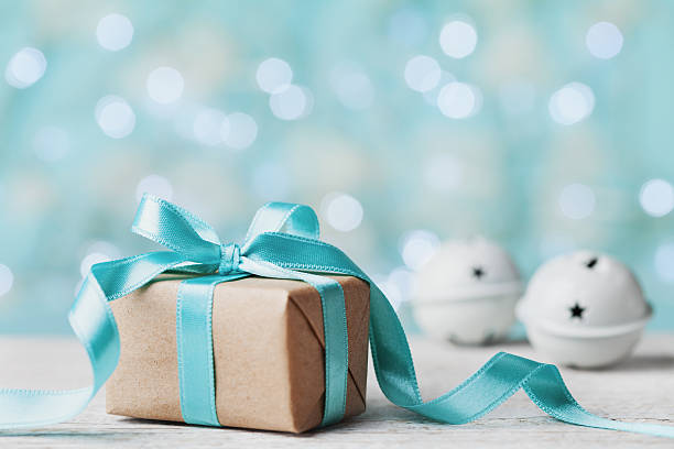 istock Christmas gift box and jingle bell against turquoise bokeh background. 625143570