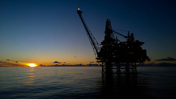 impianto di perforazione petrolifera al tramonto - oil industry oil rig fuel and power generation tower foto e immagini stock