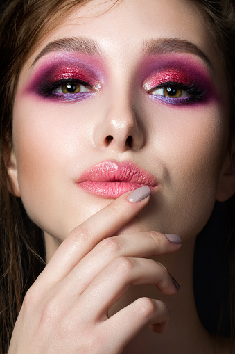 Closeup portrait of young beautiful woman with bright pink smokey eyes and lips. Fashion makeup. Studio shot. Modern summer make up