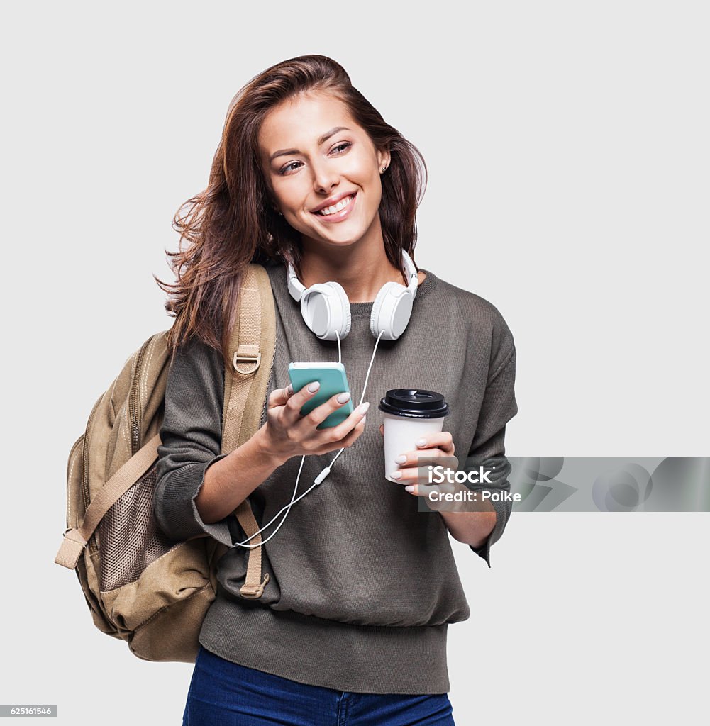 Happy young student girl using smart phone Happy young traveler girl holding smartphone and coffee Women Stock Photo