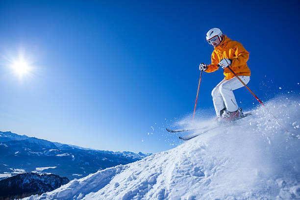 skier with black skis skiing off the beaten track in front of blue sky