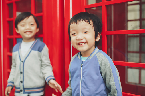 Children with red telephone box in the city 