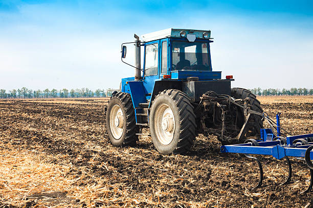 istock Old blue tractor with a plow in a field. 625189234