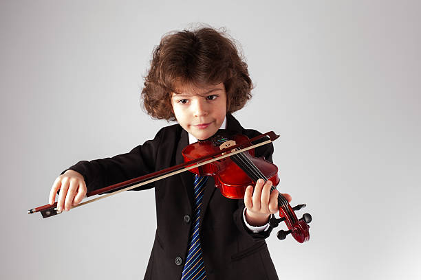 istock Small curly boy is playing a concert on the violin 625192780