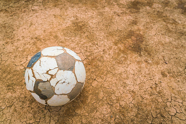 Old football on dry cracked earth