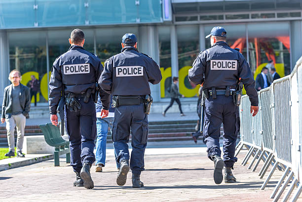 tree police officers walking in the street La defense, France - April 10, 2014: Back view of tree police officers walking in the center of La defense, great business block near Paris. national express stock pictures, royalty-free photos & images