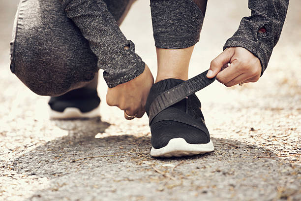 Female runner fastening velcro closure of shoe Low section of female runner fastening velcro closure of her sports shoe preparing for a jog. nylon fastening tape stock pictures, royalty-free photos & images