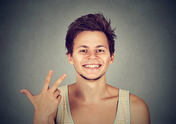 man giving a three fingers sign gesture with hand man giving a three fingers sign gesture with hand isolated on gray background triumvirate stock pictures, royalty-free photos & images