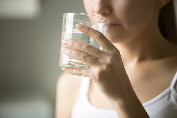 female drinking from a glass of water - drinking water stockfoto's en -beelden