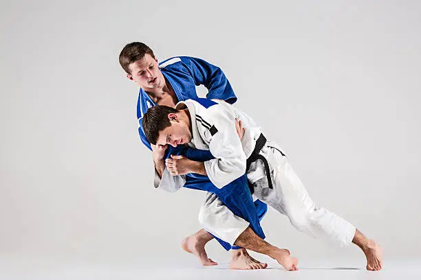 The two judokas fighters fighting men on gray studio background