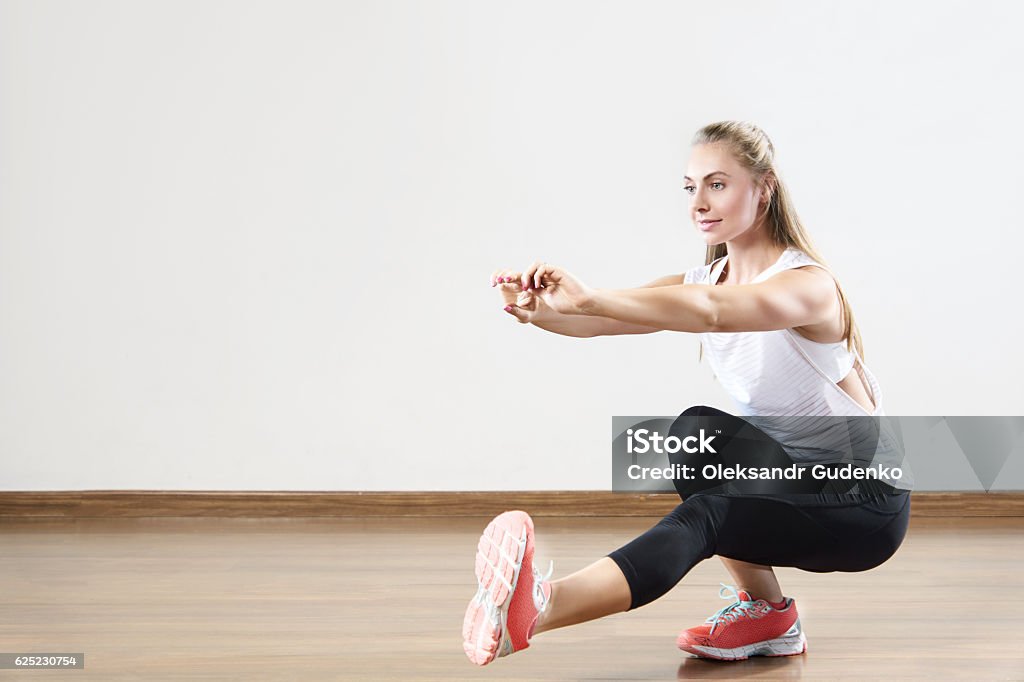 Young fit woman works out in the fitness class. Young fit woman works out in the fitness class. Squats on one leg. Space for placing text. Activity Stock Photo