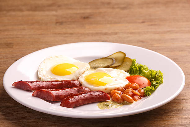 istock Fried eggs with bacon sausages and greens 625235042