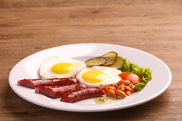 istock Fried eggs with bacon sausages and greens 625235082
