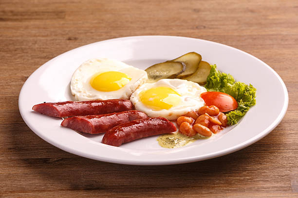 istock Fried eggs with bacon sausages and greens 625235164