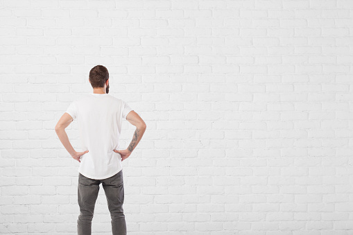 Man looking at aged paint white brick wall background