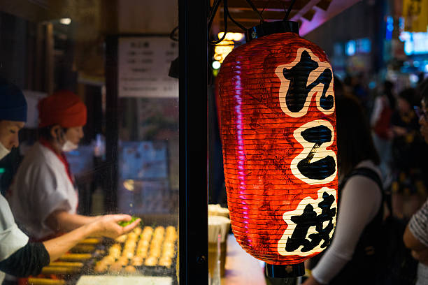 Takoyaki shop in Osaka Osaka, Japan - October 26, 2016: Takoyaki, ball-shaped Japanese snack made of a wheat flour-based batter and octopus, shop at Dotonbori street in Osaka cooking takoyaki is a ball shaped japanese snack stock pictures, royalty-free photos & images