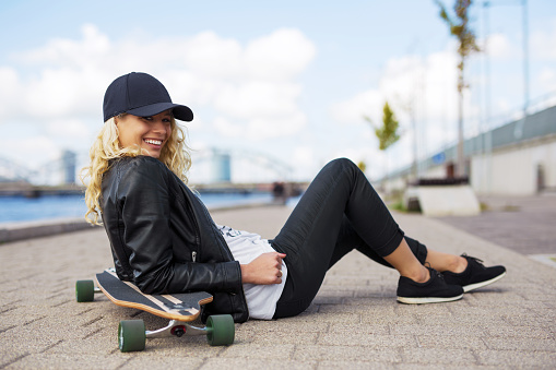 Woman with longboard sitting on the ground