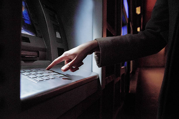 istock Female using  ATM at night on the street 625271980