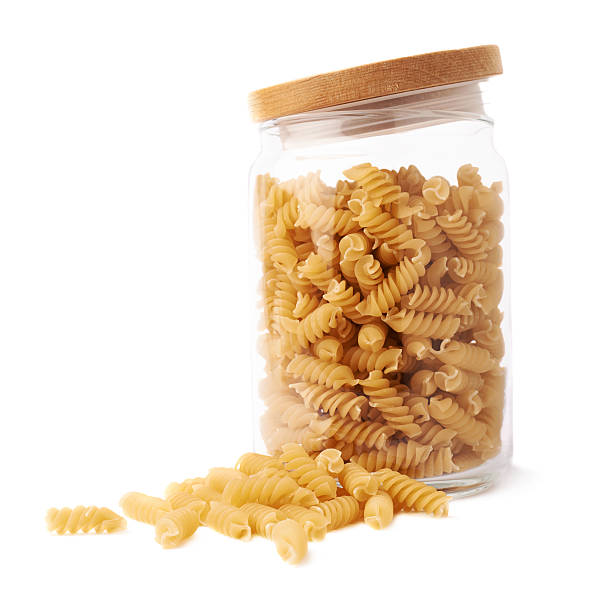 istock Glass jar filled with dry rotini pasta over isolated white 625280900