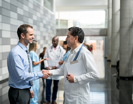 Handshake of a doctor and a business man closing a deal - Medical insurance concepts