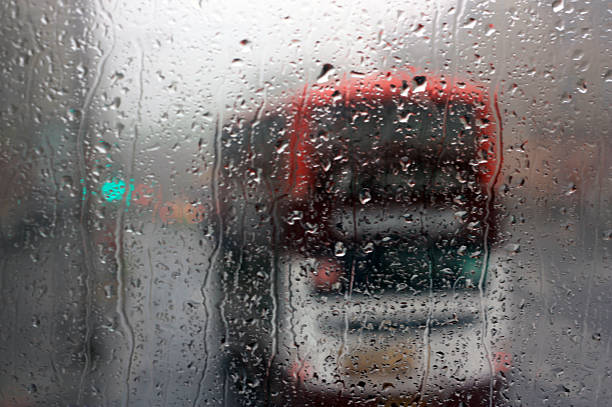 Window glass with rain drops and British bus outside in Great Britain.