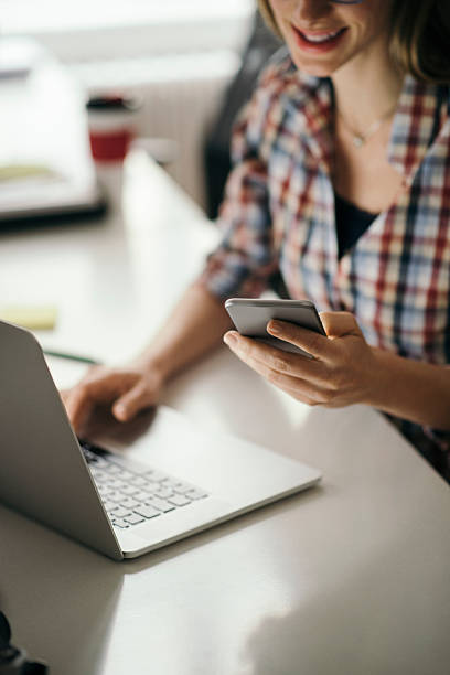 istock Smiling woman using phone at office desk 625284344