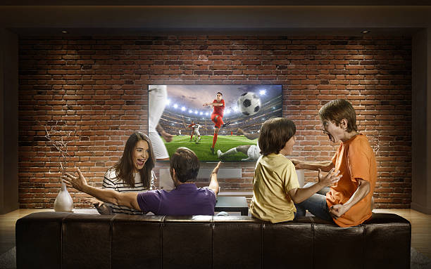 家族は自宅でサッカーの試合を見ています - fan television football watching tv ストックフォトと画像