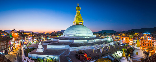 The iconic mandala dome of Boudhanath stupa, illuminated by spotlights as crowds of pilgrims and tourists walk around the ancient Buddhist shrine, a UNESCO World Heritage Site in Kathmandu, Nepal's vibrant capital city.